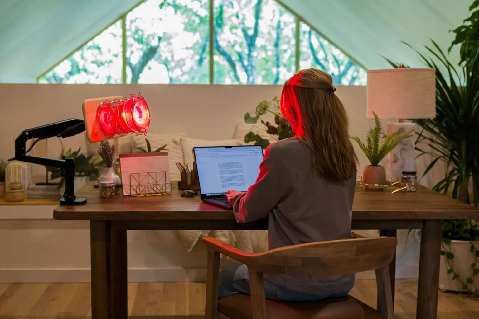 Woman using SaunaSpace Glow red light therapy at desk for focus and screen fatigue relief